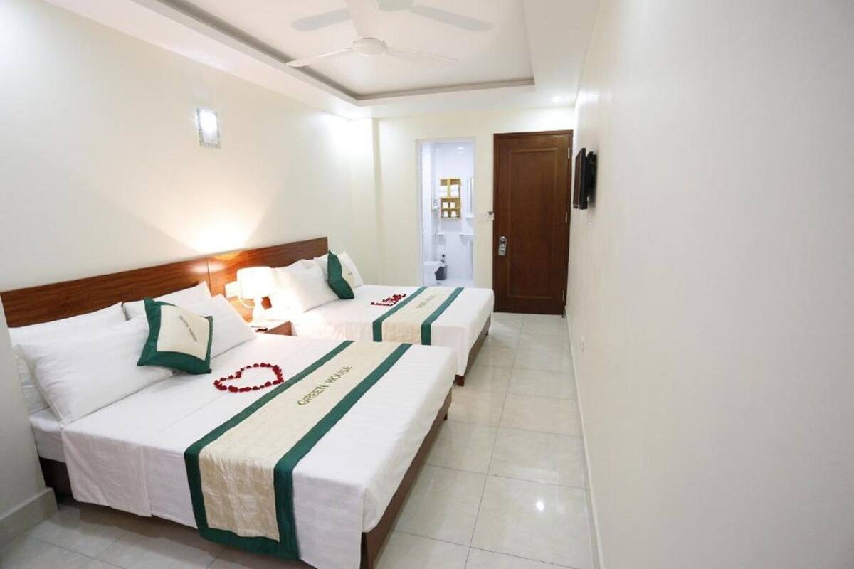 A hotel room with two beds, a ceiling fan, and a door leading to a bathroom.