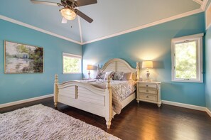 A bedroom with a bed, nightstands, a ceiling fan, and a window.