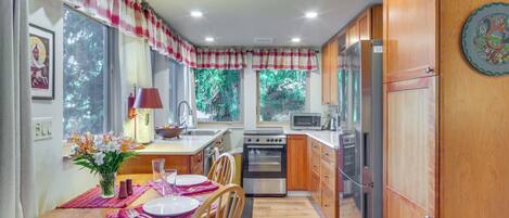 A compact kitchen with wooden cabinets, a microwave, a stove, and a refrigerator.