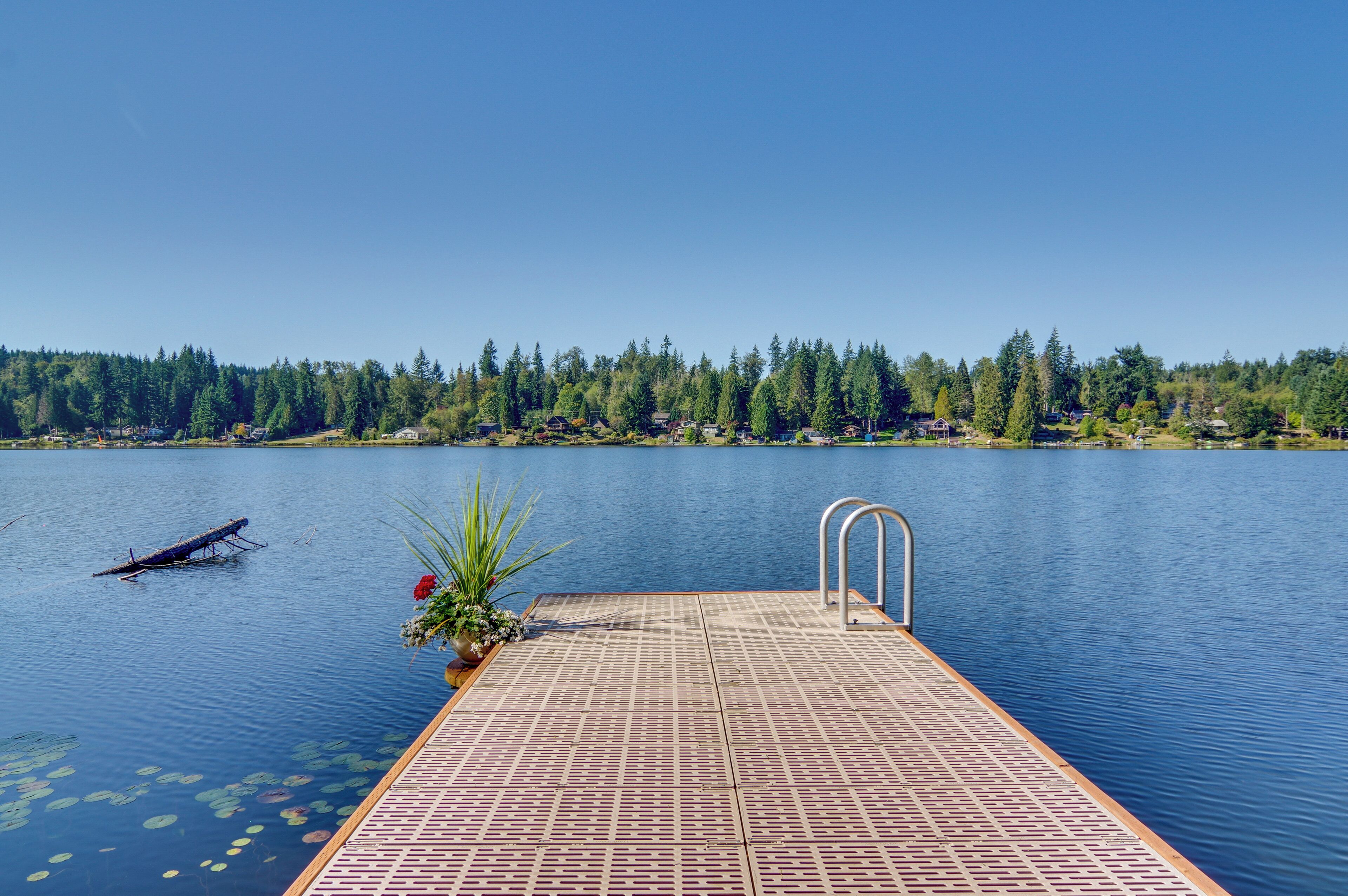 Une jetée en bois s’étendant sur un lac paisible, sous un ciel dégagé.