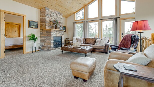 A spacious living room with a stone fireplace, leather furniture, and large windows. - Jefferson Mountain Cabin w/ Private Deck & Grill! (Como)
