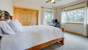 A bedroom with a wooden bed, a ceiling fan, a desk with a chair, and a large window with curtains. - Jefferson Mountain Cabin w/ Private Deck & Grill! (Como)