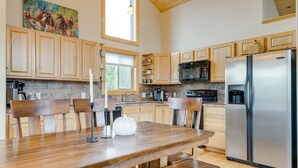A modern kitchen with wooden cabinets, a stainless steel refrigerator, and a dining table with benches. - Jefferson Mountain Cabin w/ Private Deck & Grill! (Como)