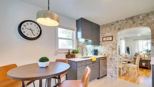 Une cuisine moderne avec un coin repas, un mur recouvert de pierres apparentes et une horloge au mur.