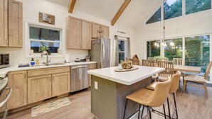 Een moderne keuken met houten kastjes, roestvrijstalen apparatuur en een groot kookeiland met barstoelen.