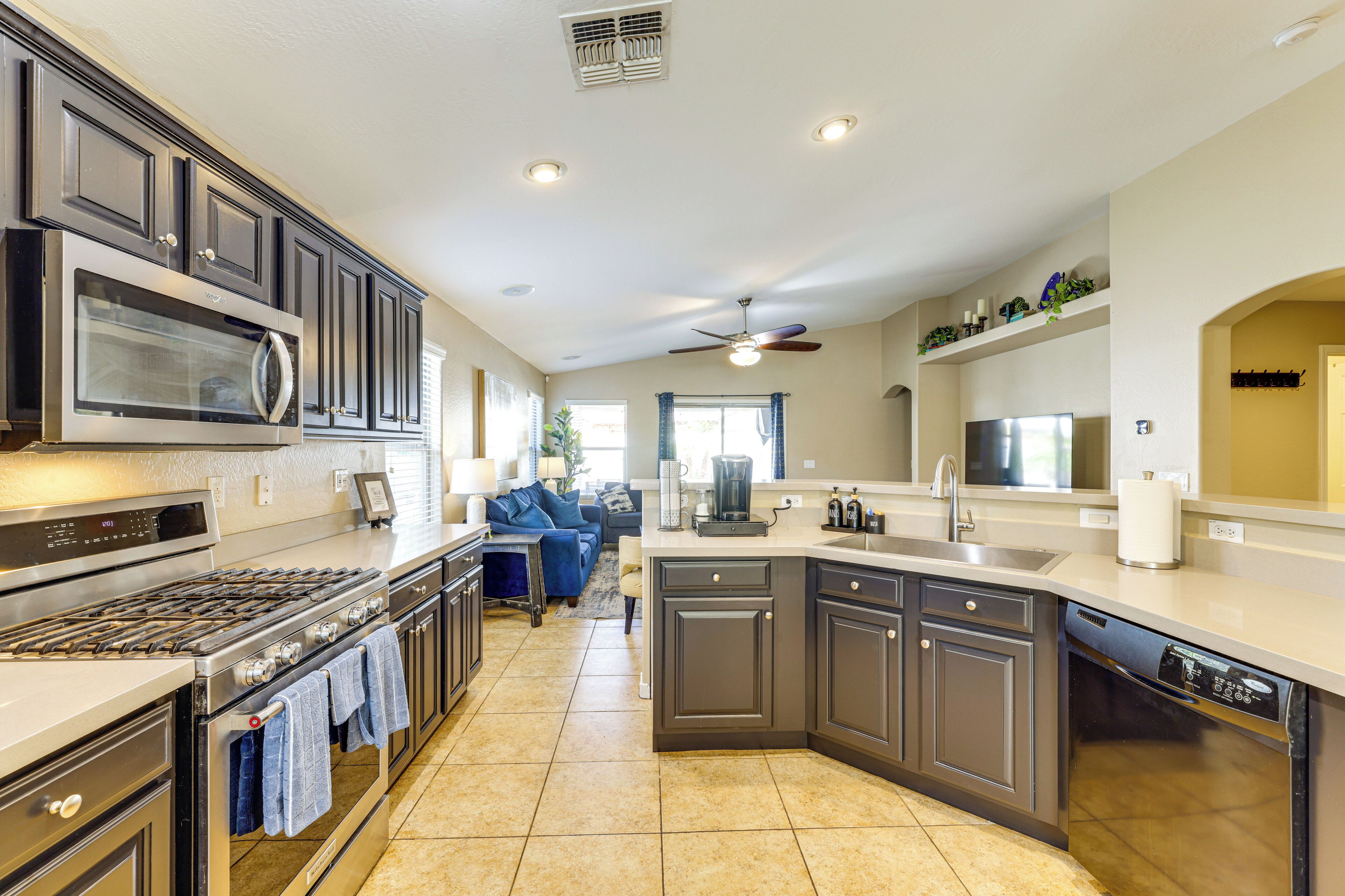 A modern kitchen with dark cabinetry, stainless steel appliances, and a central island.