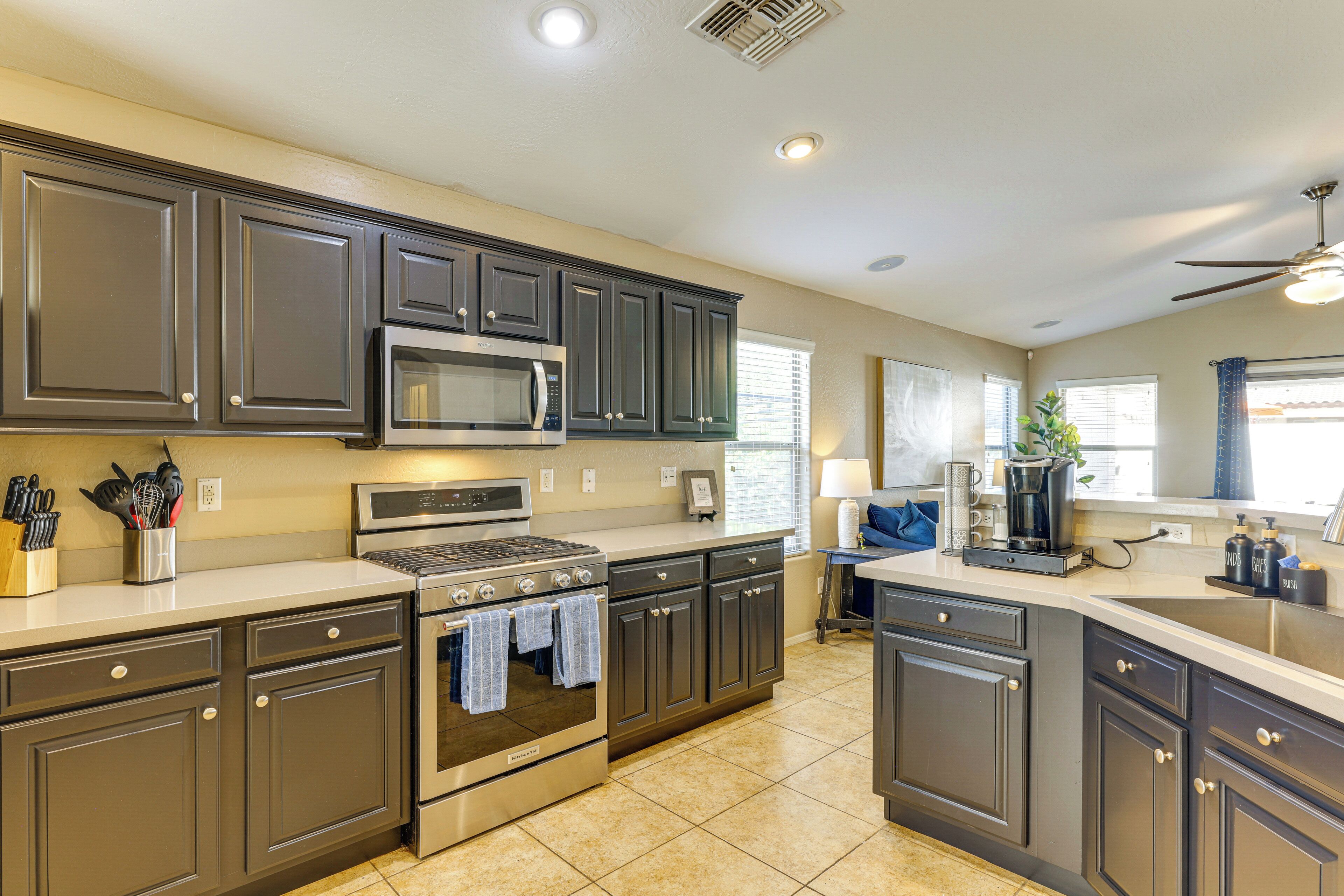 A modern kitchen with dark cabinets, stainless steel appliances, and a large island with a sink.