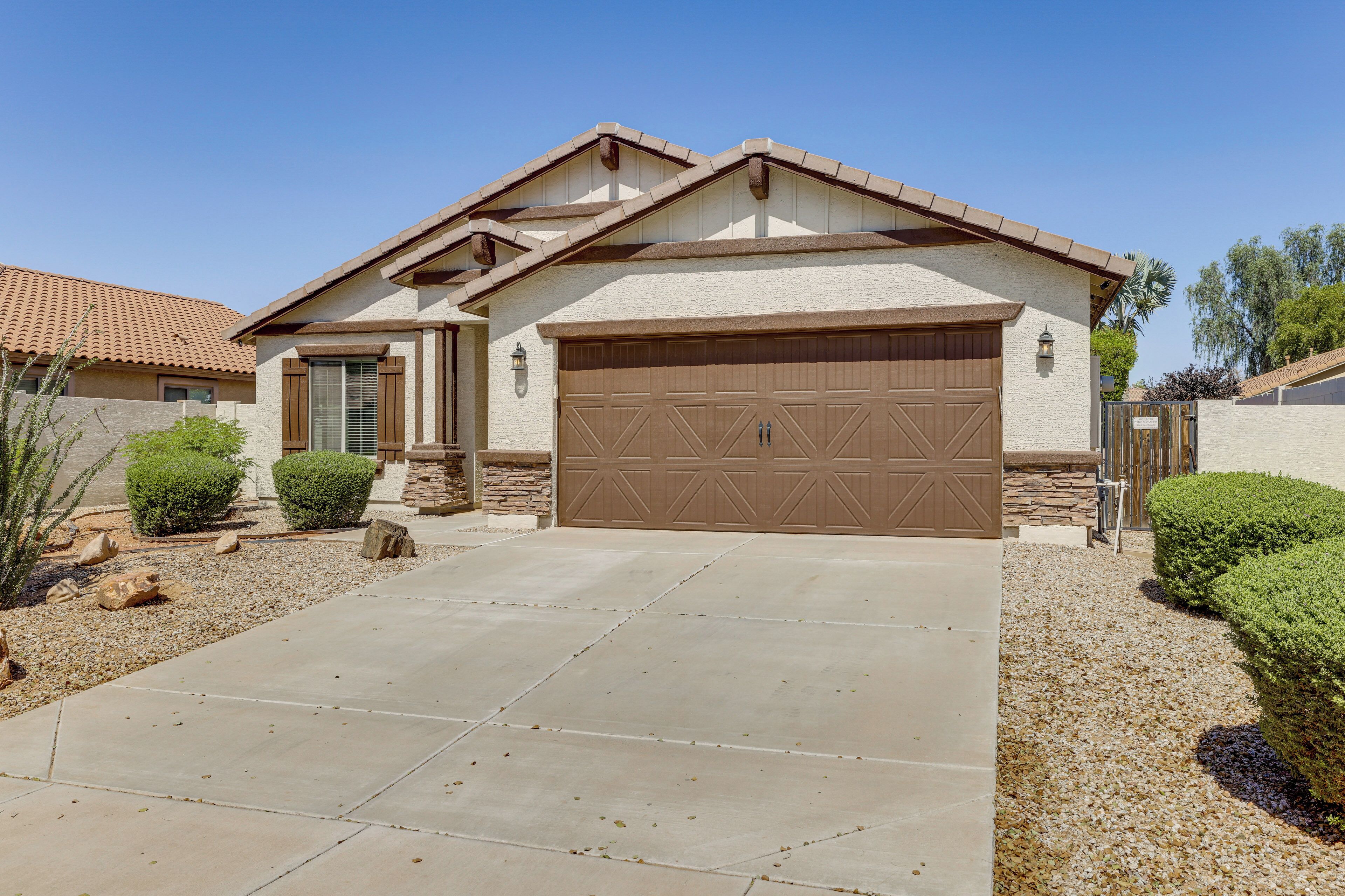 A residential house with a large garage, a stone foundation, and a well-maintained driveway.