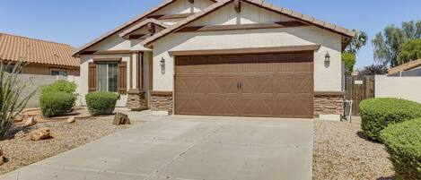 A residential house with a large garage, a stone foundation, and a well-maintained driveway.