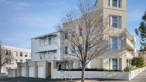 Kerrostalo, jossa on tasainen julkisivu, keskeinen sisäänkäynti ja pieni puu etualalla.
