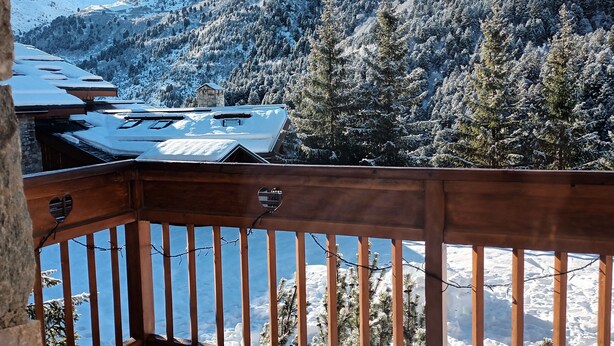 A balcony with a view of snow-covered mountains and trees.
