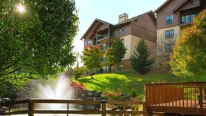Ein mehrstöckiges Gebäude mit Balkonen, einem Teich mit Springbrunnen und einer Holzterrasse.