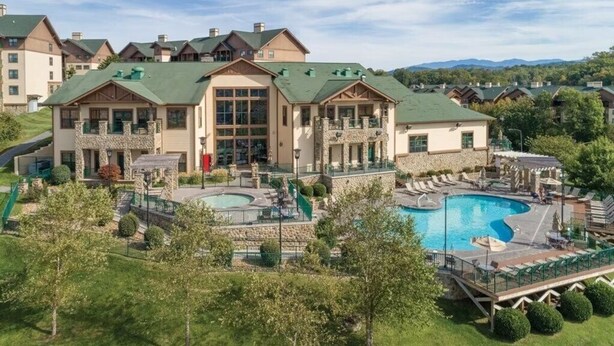 Ein Resort mit mehreren Gebäuden, einem großen Schwimmbecken und einer gepflegten Rasenfläche.