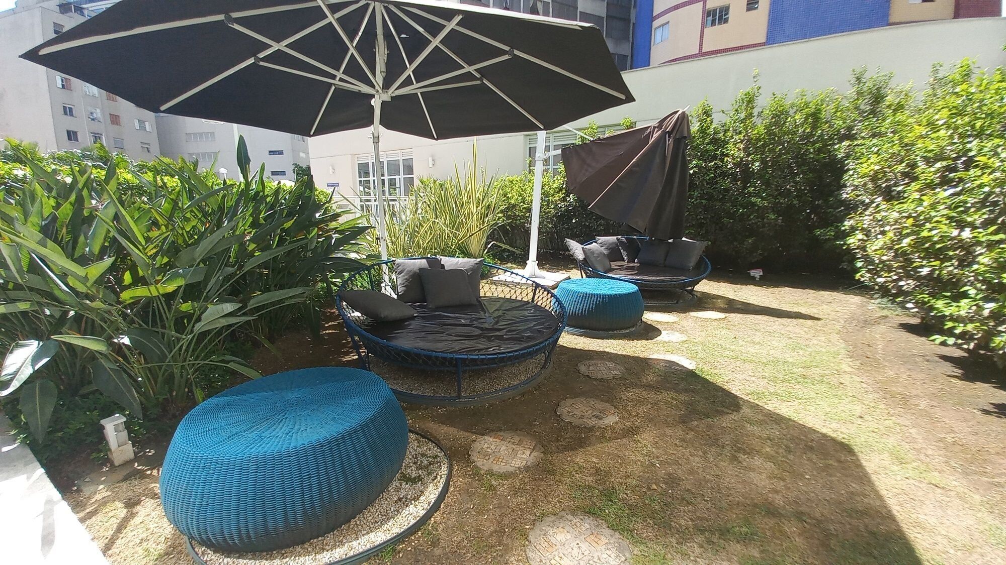 An outdoor seating area with round blue chairs and a large umbrella.