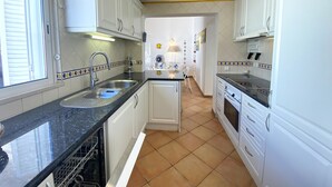 A kitchen with white cabinets, a black countertop, and a tiled floor.
