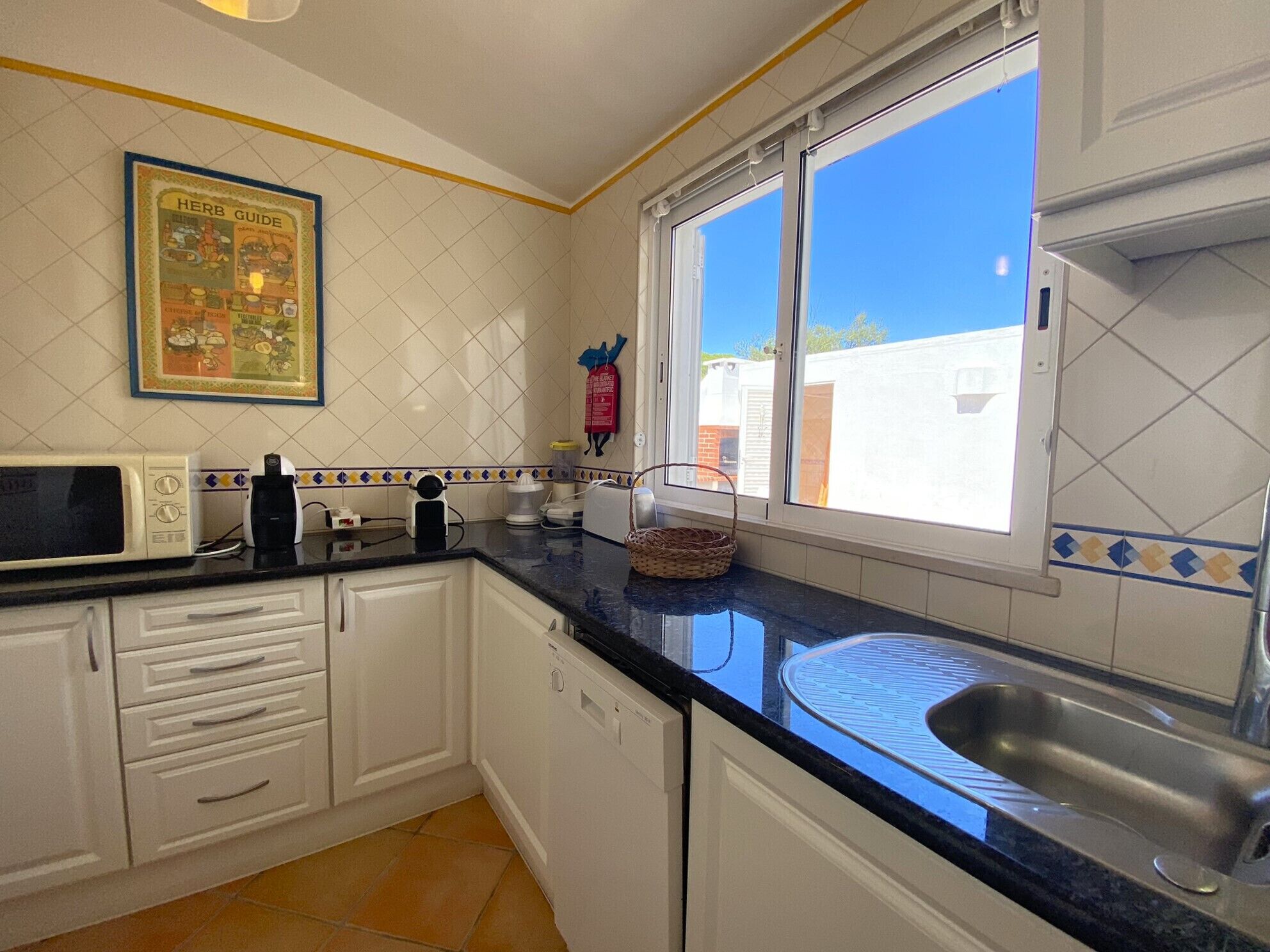 A kitchen with white cabinets, a microwave, a toaster, and a sink.