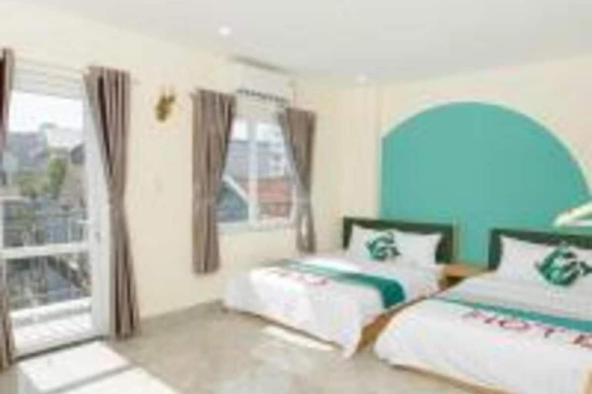 A hotel room with two beds, a large window, and a view of the city.