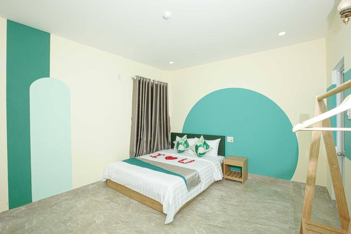 A bedroom with a bed, a nightstand, a wooden ladder, and a large teal wall.