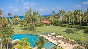 A swimming pool with lounge chairs and umbrellas, surrounded by palm trees and a view of the ocean. - Villa Kyneos, prestigious villa on the beach at Cap Est Martinique  (Le François)