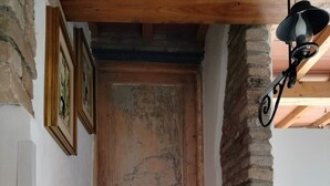 A staircase leading to a wooden door with a rustic appearance, a wall-mounted light fixture, and a brick column. - Romantic Penthouse with Terrace - San Remo 5 minutes from the center CITRA 008055-LT-2187 (Sanremo)