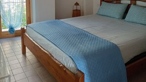 A bedroom with a wooden bed, a hanging light fixture, a stone wall, and a window with a curtain. - Romantic Penthouse with Terrace - San Remo 5 minutes from the center CITRA 008055-LT-2187 (Sanremo)