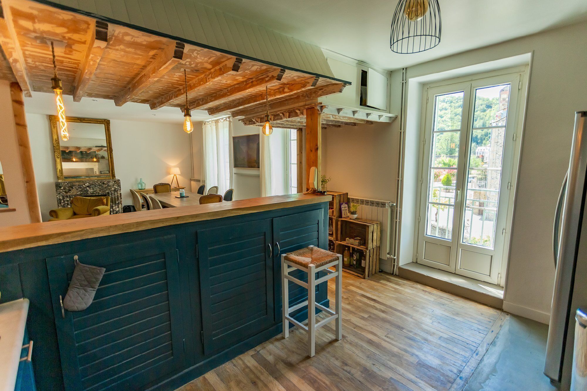 A kitchen with a wooden ceiling, a bar area, and a view of greenery outside.