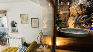Ein gemütliches Wohnzimmer mit einem grünen Sofa, einem Glastisch und einer Steinwand mit Whirlpool.