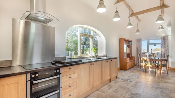 A modern kitchen with wooden cabinets, stainless steel appliances, and pendant lighting. - The Old Greenhouse - UK45328 (Wragby)