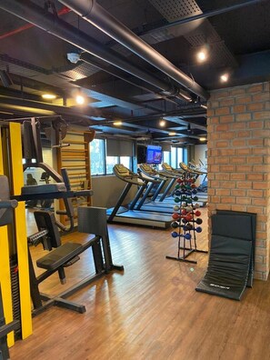 Een sportschool met loopbanden, krachttoestellen en een kettlebellrek.