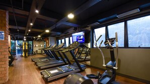 A gym with treadmills, ellipticals, and a weight machine. - Elegance Suites Ibirapuera (São Paulo)
