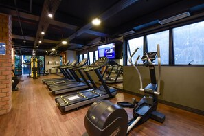 Une salle de sport équipée de tapis de course, de vélos elliptiques et d’une machine de musculation.