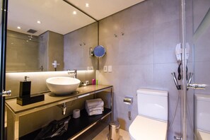 Une salle de bain moderne avec un grand lavabo, un miroir et une douche.