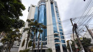 A modern high-rise building with a glass facade, surrounded by palm trees and a pedestrian crossing. - Elegance Suites Ibirapuera (São Paulo)