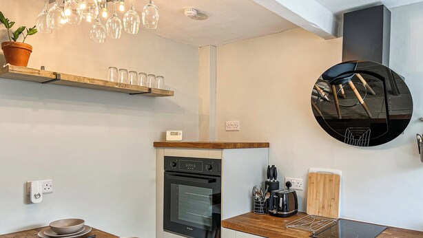 Une cuisine moderne dotée d’un plan de travail en bois, d’un four encastré et d’une plaque de cuisson à induction noire.