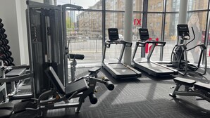 Ein Fitnessstudio mit Laufbändern, Kraftgeräten und Hanteln.
