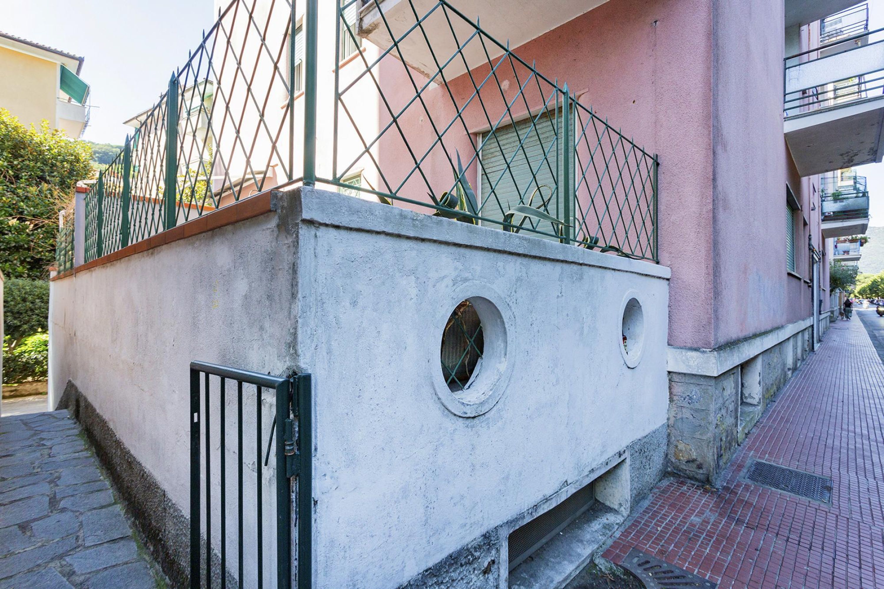 Ein Gebäude mit Betonfundament, einem Metallzaun und einem kleinen Rundfenster.