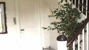 Una escalera con barandilla blanca y una planta en maceta al pie.