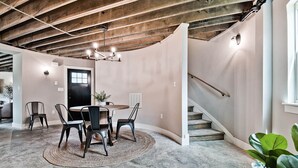 A dining area with a round table, four chairs, a woven rug, and a staircase with a handrail. - HJ's Silos (Fayetteville)