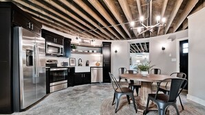 A modern kitchen with stainless steel appliances, a wooden ceiling, and a dining area with a round table and chairs. - HJ's Silos (Fayetteville)
