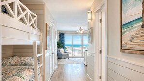A hallway with bunk beds, a ceiling fan, and a view of the ocean through large windows. - Gulf View Family Getaway, Amazing Pool, Short walk to Beach & Pier Park (Panama City Beach)
