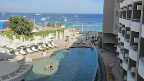 Ein Hotelpoolbereich mit Blick auf das Meer und Boote.