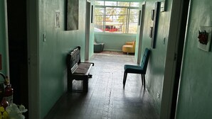 A hallway with a bench, a chair, and a small table. There are pictures on the walls and a window at the end of the hallway. - Pousada da Praia (Sao Vicente)