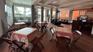 A restaurant with tables and chairs, a counter, and a television. - Pousada da Praia (Sao Vicente)