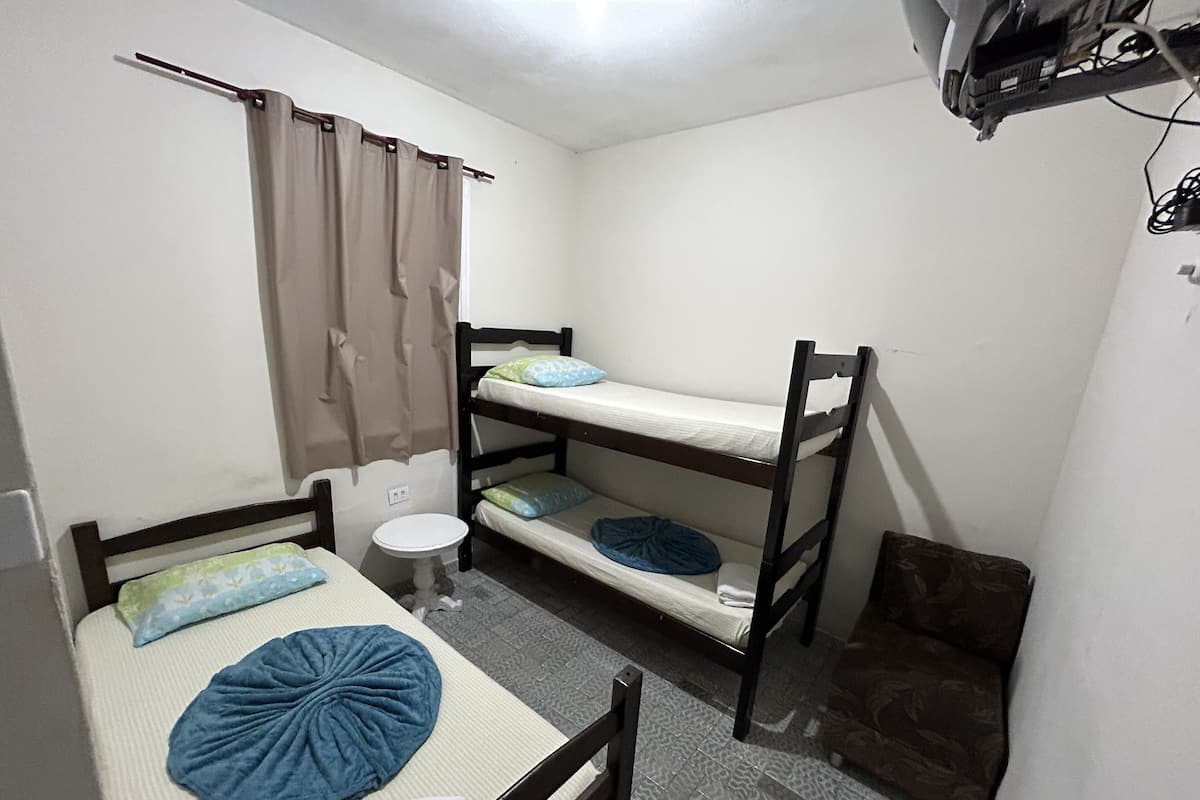 A dormitory room with bunk beds, a small round table, and a curtain.