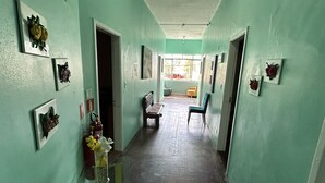 A hallway with green walls, wooden flooring, and several framed pictures. There are chairs and a table in the center. - Pousada da Praia (Sao Vicente)