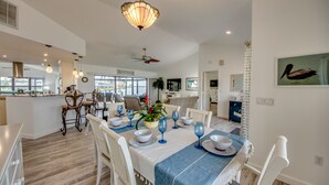 A dining area with a table set for four, white chairs, and a blue table runner. - Beautiful views, watch the dolphins and tarpon swim by on the  lanai or dock! (Cape Coral)