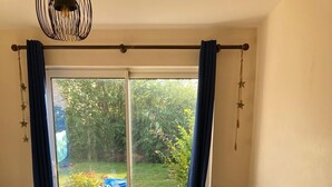 A dining area with a wooden table and four chairs, a sliding glass door to the outdoors, and a hanging light fixture. - Stunning 3 -bed Semi Detached House in Cambridge (Cambridge)