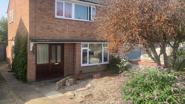A two-story brick house with a front door, windows, and a garden with gravel and plants. - Stunning 3 -bed Semi Detached House in Cambridge (Cambridge)