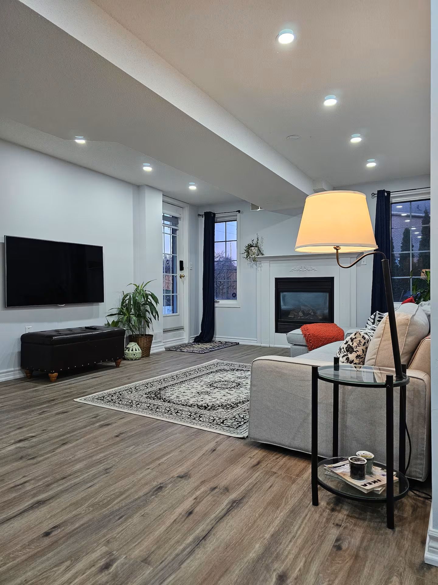 A modern living room with a flat-screen TV, a sofa, a coffee table, and a fireplace.