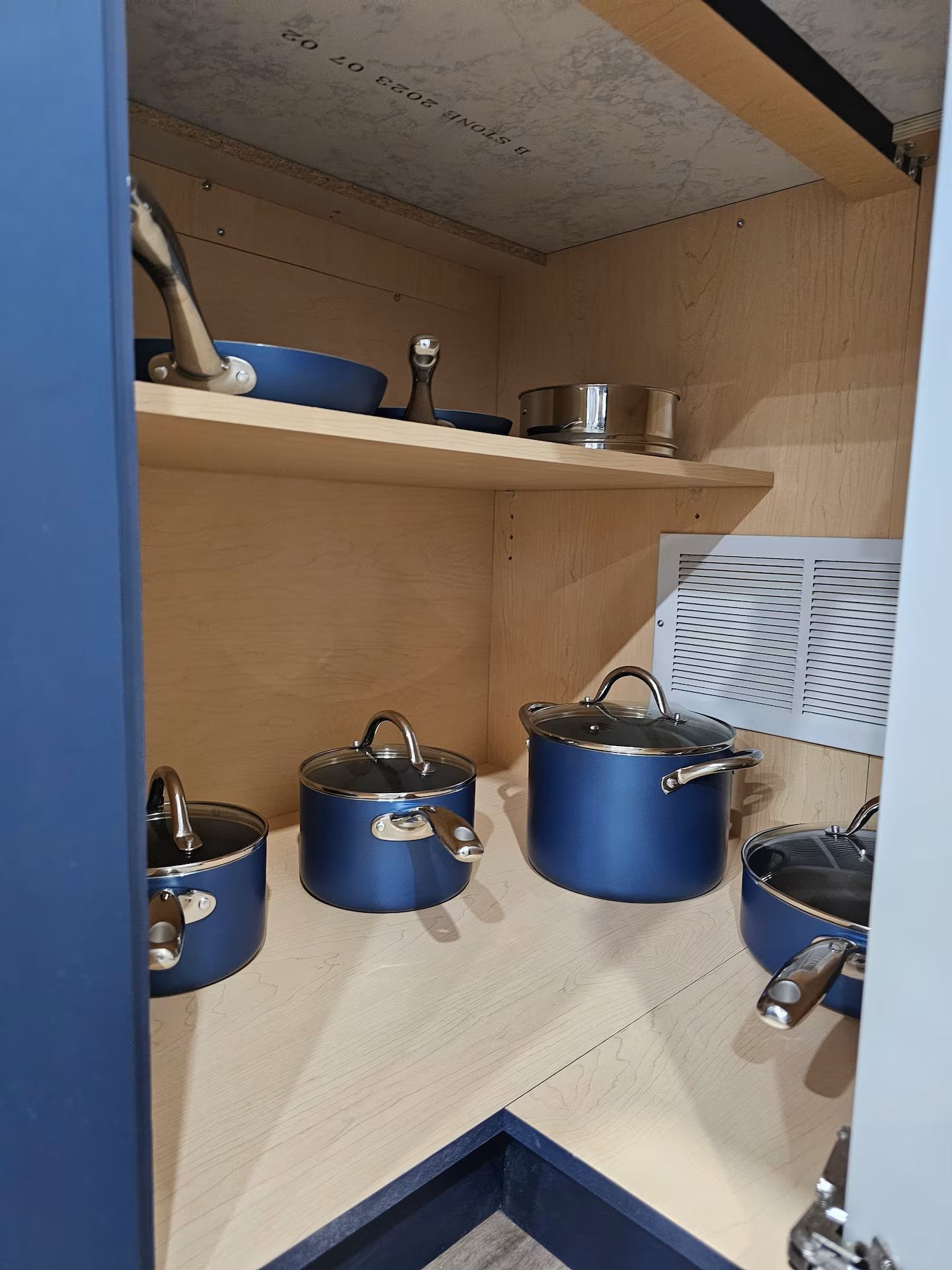 A kitchen with wooden cabinets and blue cookware.